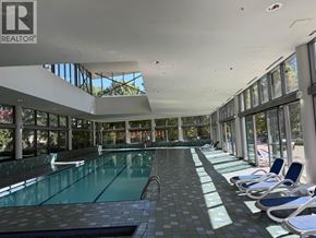 Vancouver apartment for rent - A large indoor swimming pool with lounge chairs and a glass wall.