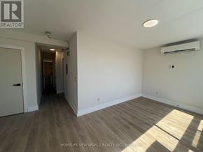 Toronto (Mimico) condo for rent - A room with wooden flooring and white walls, with a doorway leading to another room.