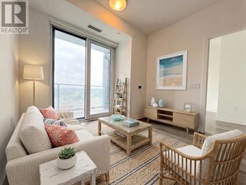 Kitchener condo for rent - A living room with a couch, a chair, a table, and a painting on the wall.
