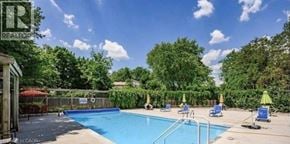 Guelph condo for rent - A pool surrounded by trees and a fence with a sign that says "REALTOR".