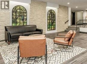 Guelph condo for rent - A living room with a black couch, a brown chair, and a patterned rug.