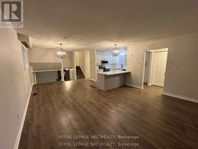 St. Catharines (Lakeport) apartment for rent - A spacious room with wooden flooring and a kitchen area in the background.