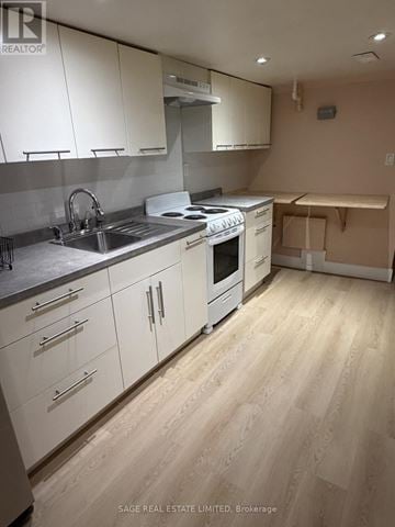 Toronto (Trinity-Bellwoods) townhouse for rent - A kitchen with white cabinets and a wooden floor.