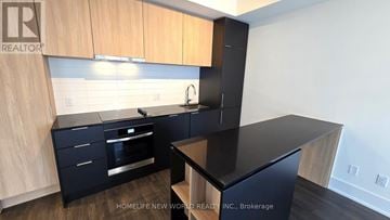 Toronto (Church-Yonge Corridor) condo for rent - A kitchen with wooden cabinets and black countertops.