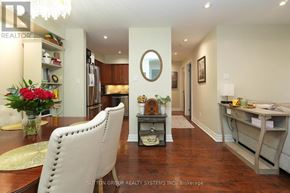 Oakville (Ga Glen Abbey) condo for rent - A well-lit, spacious kitchen and dining area with a white chair and a round mirror on the wall.