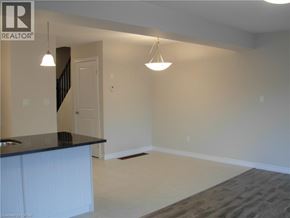Kitchener townhouse for rent - A realtor logo is on the wall of a room with a staircase.
