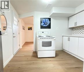 Kitchener apartment for rent - A white kitchen with a fridge, oven and a flower picture on the wall.