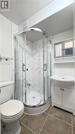 Kitchener apartment for rent - A white toilet sits next to a walk-in shower with a glass door.