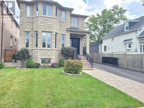 Toronto (Oakridge) apartment for rent - A house with a stone facade and a black door is surrounded by a green lawn and a wooden fence.