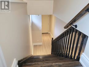 Toronto (Oakridge) apartment for rent - A staircase with a wooden handrail and steps leading to a landing with a door.