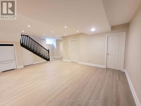 Toronto (Oakridge) apartment for rent - A spacious room with wooden flooring and a staircase.