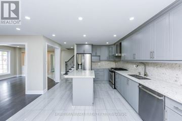 Brampton (Sandringham-Wellington) apartment for rent - A modern kitchen with white cabinets and a central island.