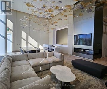 Mississauga (Port Credit) condo for rent - A modern living room with a large sectional sofa and a flat screen TV.