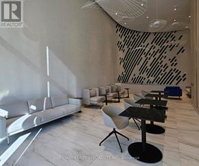 Mississauga (Port Credit) condo for rent - A modern living room with a grey sofa, black and white chairs, and a unique black and white wall art.