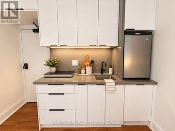 Toronto (High Park-Swansea) multi-family for rent - A kitchen with white cabinets and a stainless steel refrigerator.