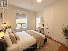 Toronto (High Park-Swansea) multi-family for rent - A bedroom with a large bed and a desk with a chair.