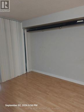 Mississauga (City Centre) condo for rent - A room with wooden flooring and white walls, with a sliding door partially open.