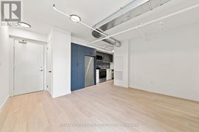 Hamilton (Corktown) multi-family for rent - A large empty room with a kitchenette in the background.