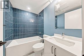 Hamilton (Corktown) multi-family for rent - A blue tiled bathroom with a white tub, toilet and sink.