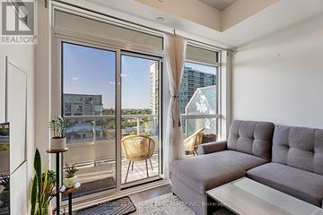 Toronto (Mimico) condo for rent - A living room with a grey couch and a large window overlooking a cityscape.