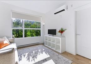 Abbotsford apartment for rent - A living room with a couch, a television, and a window with a view of trees.