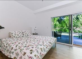 Abbotsford apartment for rent - A bedroom with a floral bedspread and a sliding glass door.