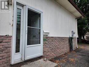 St. Catharines (Lakeport) apartment for rent - A white door with a glass window is on a white house with a brick wall.