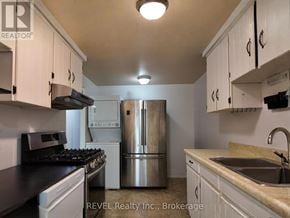 St. Catharines (Lakeport) apartment for rent - A kitchen with white cabinets and a stainless steel refrigerator.