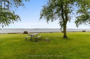 Prescott condo for rent - A grassy area with a picnic table and a tree in the foreground with a body of water in the background.
