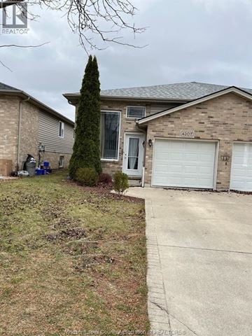Windsor apartment for rent - A house with a driveway and a tree in front.