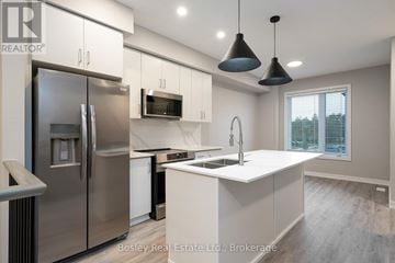 Collingwood townhouse for rent - A modern kitchen with a stainless steel refrigerator and white countertops.