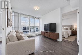 Toronto (Little Portugal) condo for rent - A living room with a couch, a television, and a bed in the background.