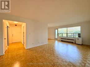 Toronto (St. Andrew-Windfields) condo for rent - A spacious room with wooden flooring and a window with a view of trees.