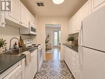 Toronto (St. Andrew-Windfields) condo for rent - A kitchen with white cabinets and a black and white floor.
