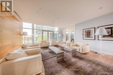 Toronto (Waterfront Communities) condo for rent - A spacious living room with white furniture and a large window.