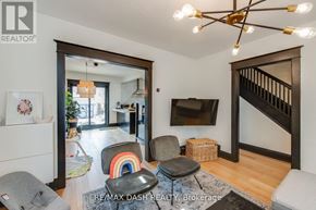 Toronto (Woodbine-Lumsden) apartment for rent - A living room with a grey couch, a black ottoman, a TV, and a wooden staircase.