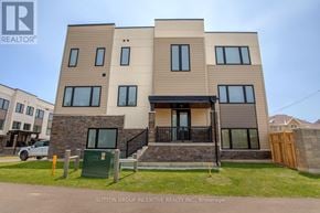 Innisfil (Lefroy) townhouse for rent - A modern two-story residential building with a balcony and a garage door.