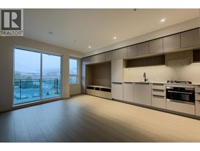 Port Moody apartment for rent - A spacious kitchen with white cabinets and a large window overlooking the city.