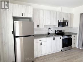 Niagara Falls (Downtown) multi-family for rent - A modern kitchen with white cabinets and stainless steel appliances.