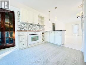 St. Catharines (Port Dalhousie) apartment for rent - A kitchen with white cabinets and a stone backsplash.