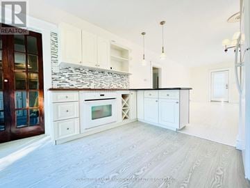St. Catharines (Port Dalhousie) apartment for rent - A kitchen with white cabinets and a stone backsplash.
