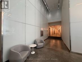 Toronto (Moss Park) condo for rent - A hallway with a glass wall on the left side and a carpeted floor with two chairs and a table.