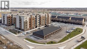 Tecumseh condo for rent - A large apartment complex with a parking lot in front.