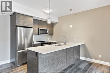 Tecumseh condo for rent - A modern kitchen with a stainless steel refrigerator and a white countertop.