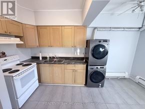 Toronto (North Riverdale) apartment for rent - A kitchen with a white stove top oven and a washing machine in the corner.