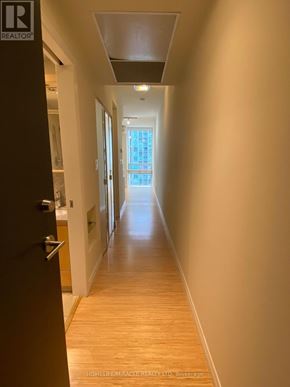 Mississauga (Fairview) condo for rent - A long hallway with a door on the left and a window in the distance.