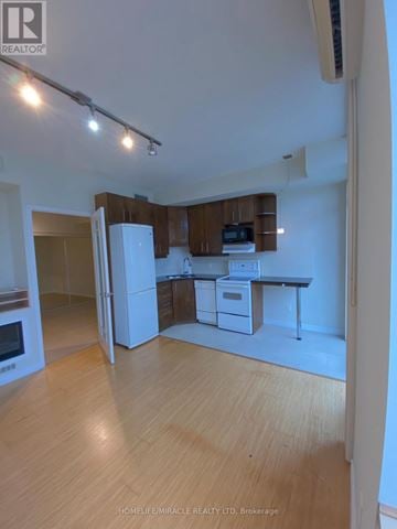Mississauga (Fairview) condo for rent - A well-lit kitchen with wooden cabinets and a white refrigerator.