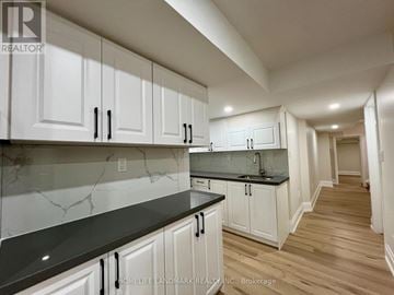 Milton (Cb Cobban) apartment for rent - A kitchen with white cabinets and black countertops.