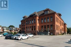 Hamilton (Stinson) condo for rent - A large red brick building with a parking lot in front of it.