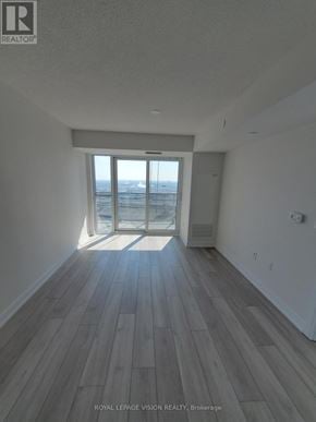 Toronto (Agincourt South-Malvern West) condo for rent - A room with wooden flooring and a large window overlooking a cityscape.